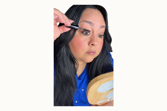 Woman wearing Reillie Beauty Soft Lift Mascara and holding the mascara tube. 
