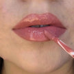 Woman with medium skin wearing Berry Glow Gloss, clear shade with nourishing botanicals