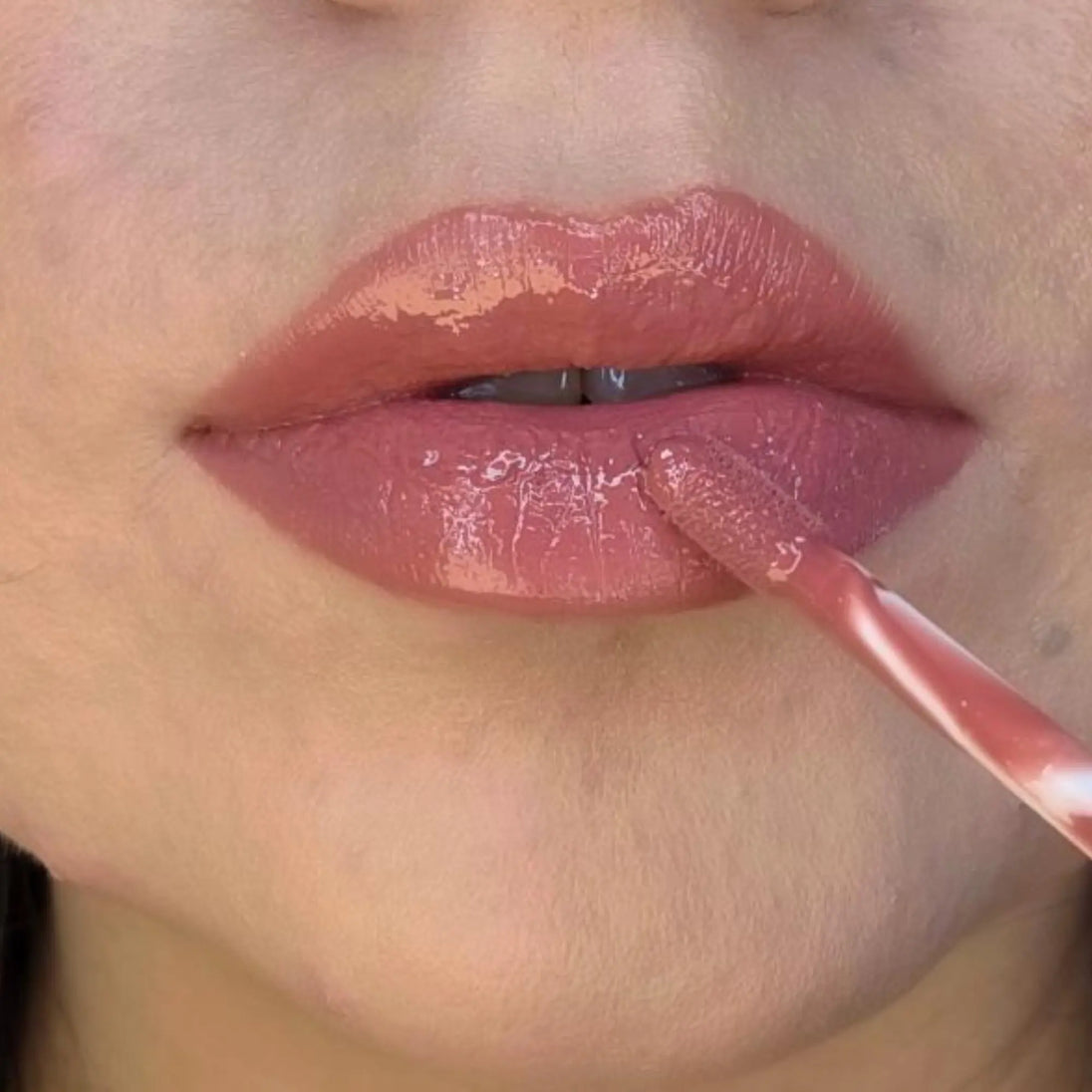 Woman with medium skin wearing Berry Glow Gloss, clear shade with nourishing botanicals