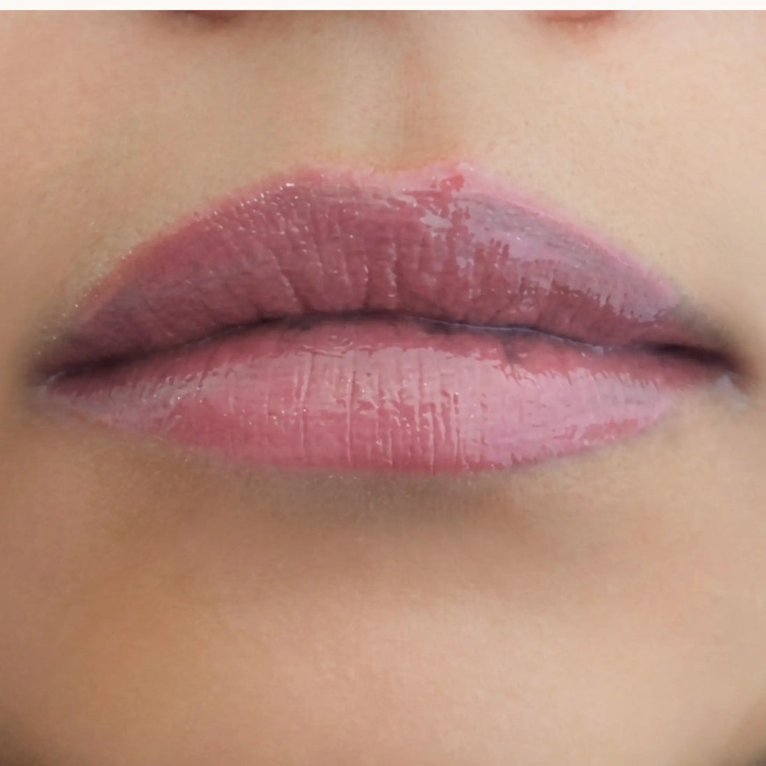 Woman with medium skin wearing Berry glow Gloss, clear shade with nourishing botanicals