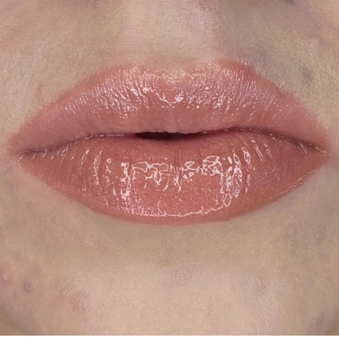 Woman with fair skin wearing Caramel Lip Gloss, clear shimmering shade with nourishing botanicals