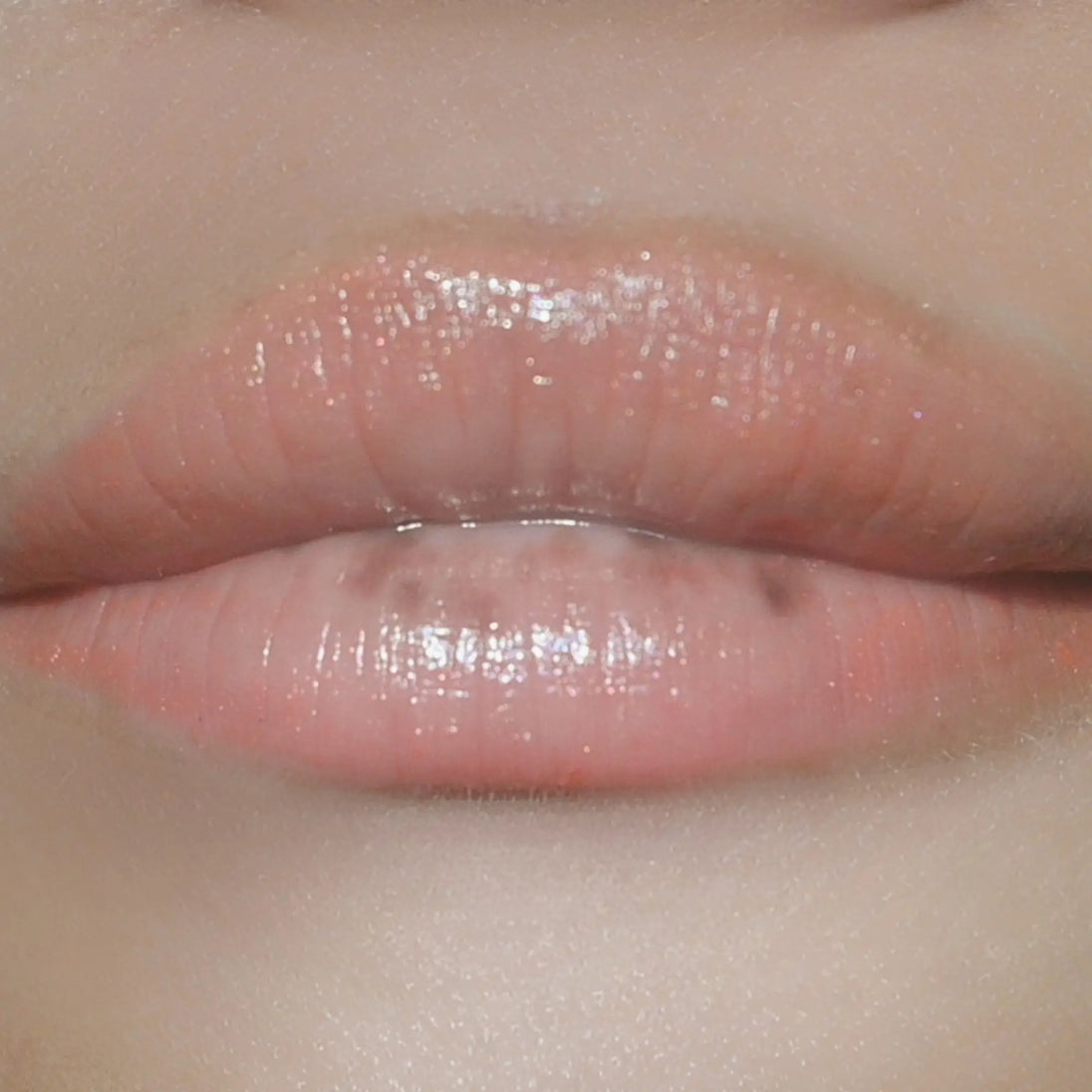 Woman with medium skin wearing cinnamon Lip Gloss, clear shimmering shade with nourishing botanicals
