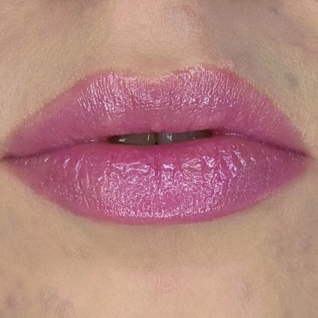 Woman with fair skin wearing Dragon Fruit Lip Gloss, clear shimmering shade with nourishing botanicals.