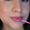Woman with fair skin wearing Dragon Fruit Lip Gloss, fuchsia shimmering shade with nourishing botanicals