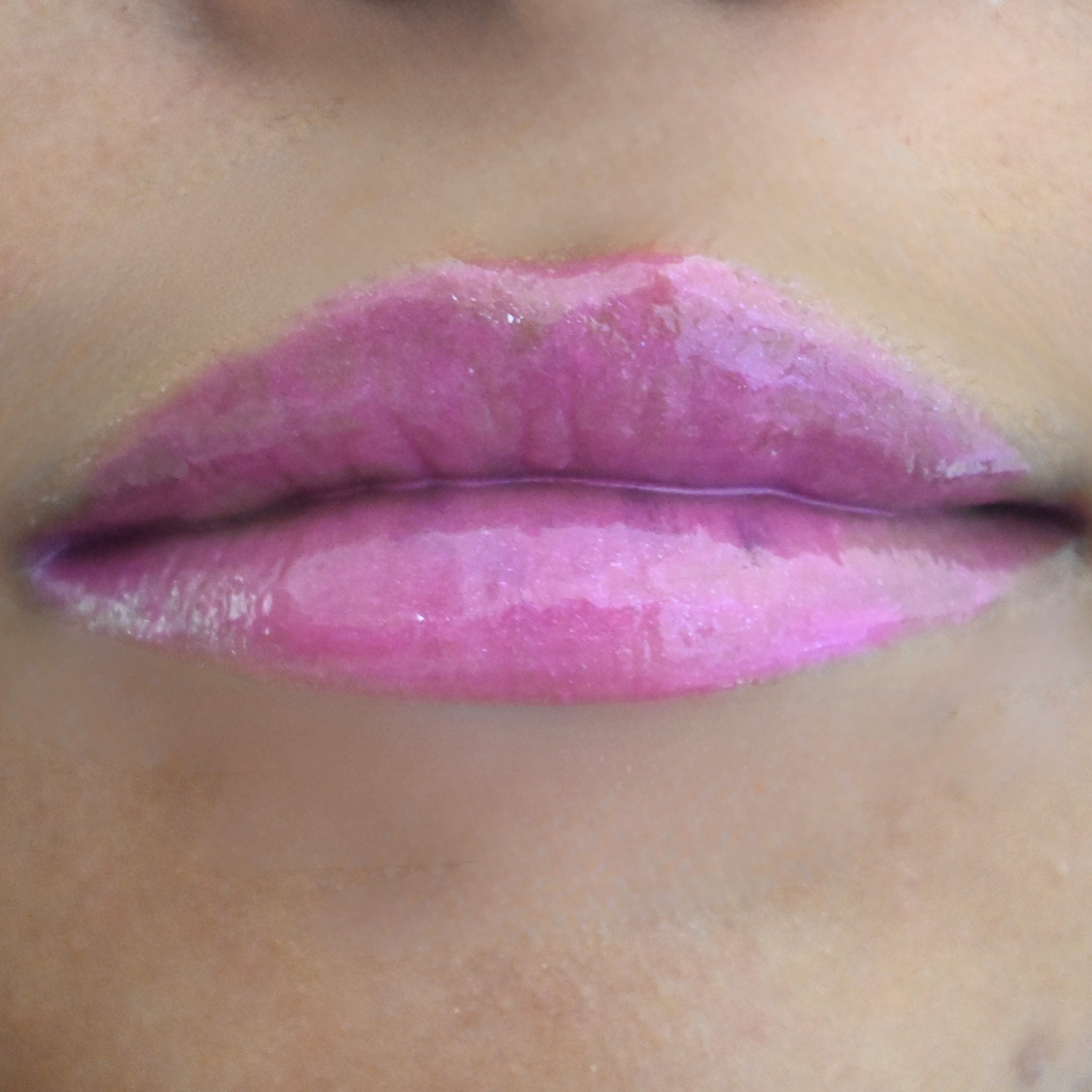Woman with medium skin wearing Dragon fruit Gloss, clear shimmering shade with nourishing botanicals