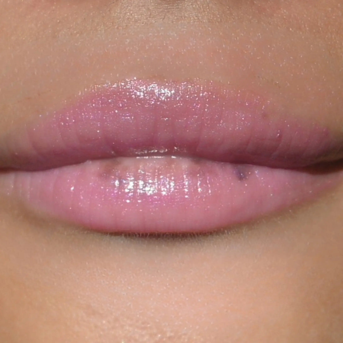 Woman with medium skin wearing Dragon fruit Gloss, clear shimmering shade with nourishing botanicals