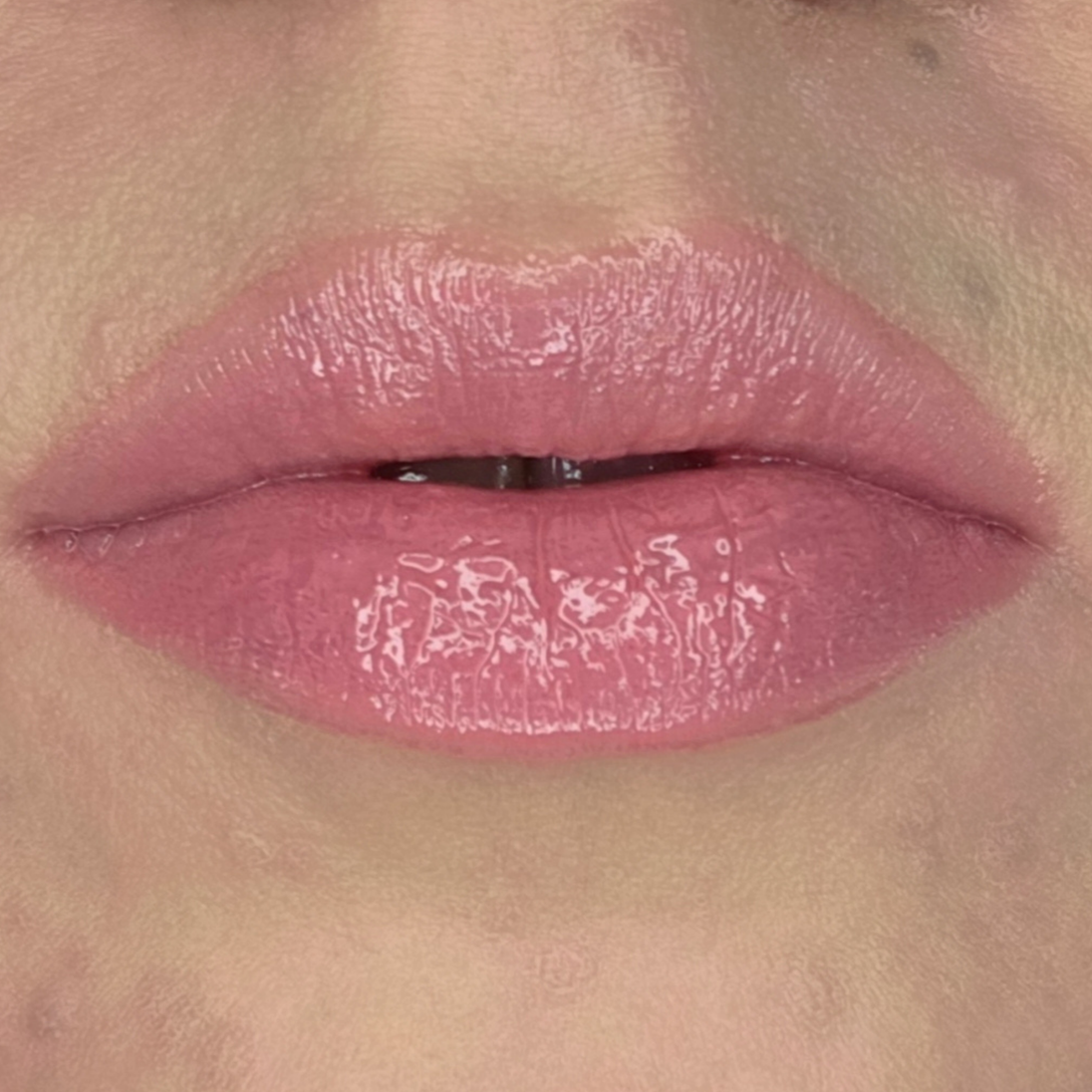 Woman with fair skin wearing Luscious Guava Lip Gloss, clear shimmering shade with nourishing botanicals