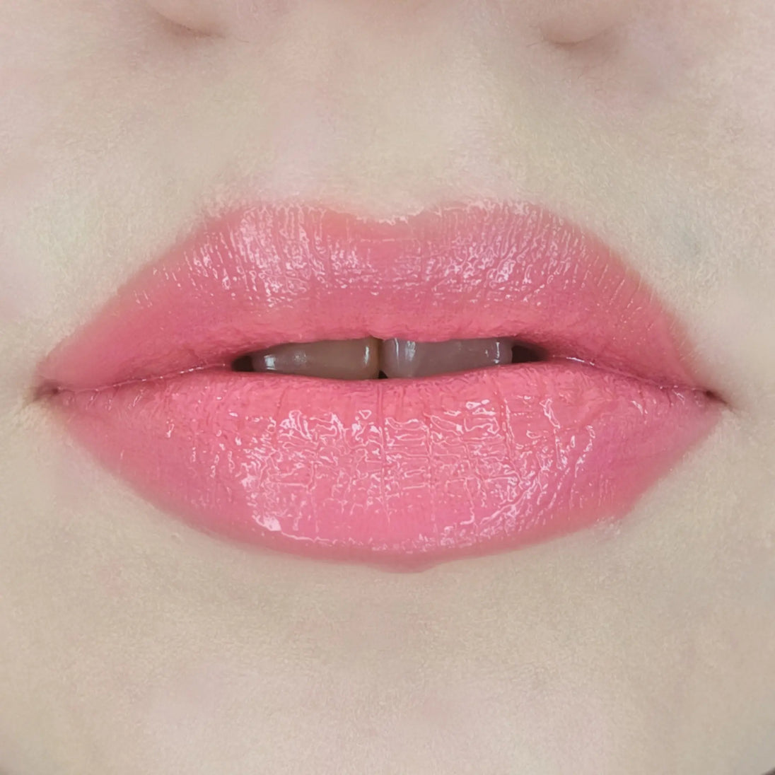 Woman with fair skin wearing luscious guava Lip Gloss, clear shimmering shade with nourishing botanicals