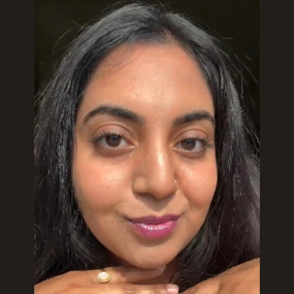 A close-up of a woman wearing comfort lip gloss shade dragon fruit and soft lift mascara.