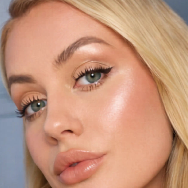 Close-up of a woman's face with highlighter on her cheek.