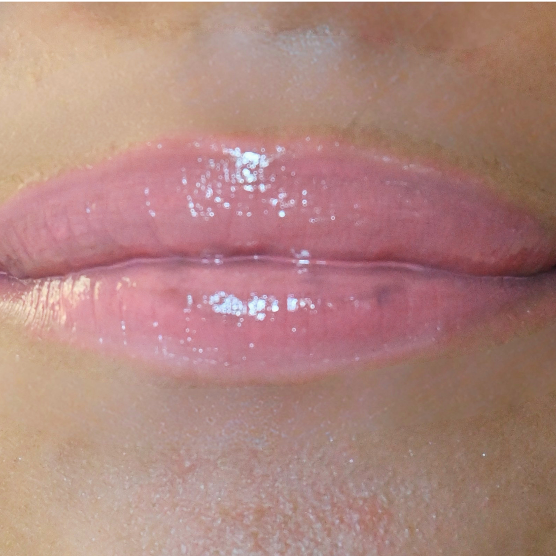 Woman with medium skin wearing luscious guava Lip Gloss, clear shade with nourishing botanicals