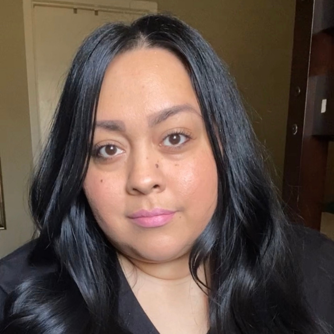 Woman with dark skin applying Reillie Beauty Organic Lipstick in Peony, bright pink shade with nourishing botanicals

