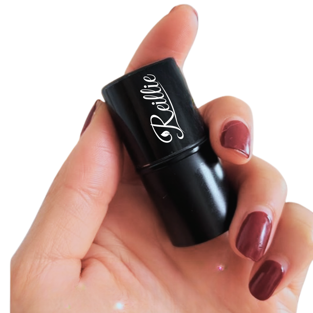 Reillie Beauty Amber Highlighter Tint in compact tube held by hand