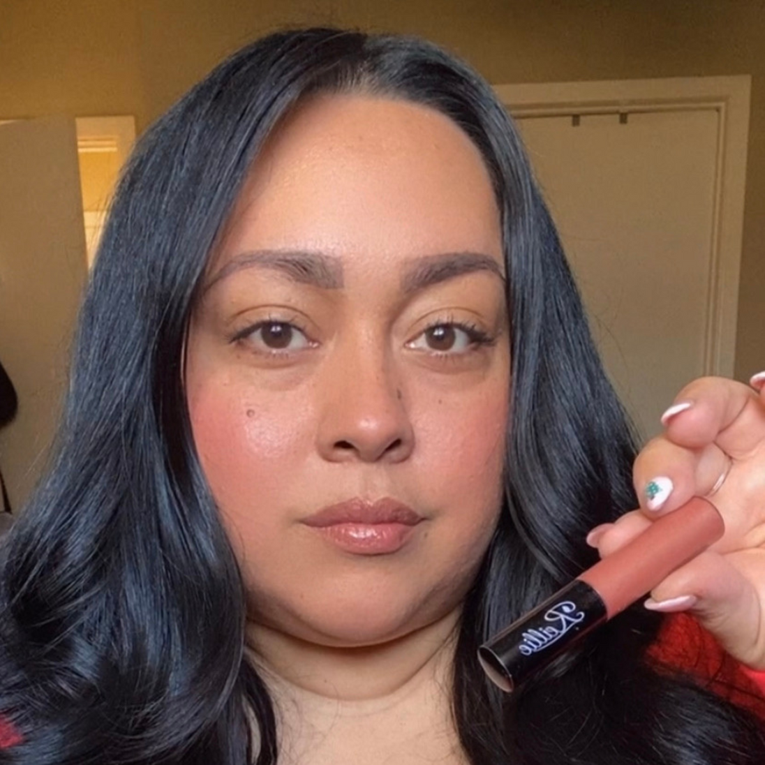 Woman with dark skin wearing Reillie Beauty Organic Lip Gloss in Caramel, warm caramel shimmering shade with nourishing botanicals