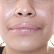 Woman with medium skin wearing Creamy Vanilla Lip Gloss, clear shimmering shade with nourishing botanicals