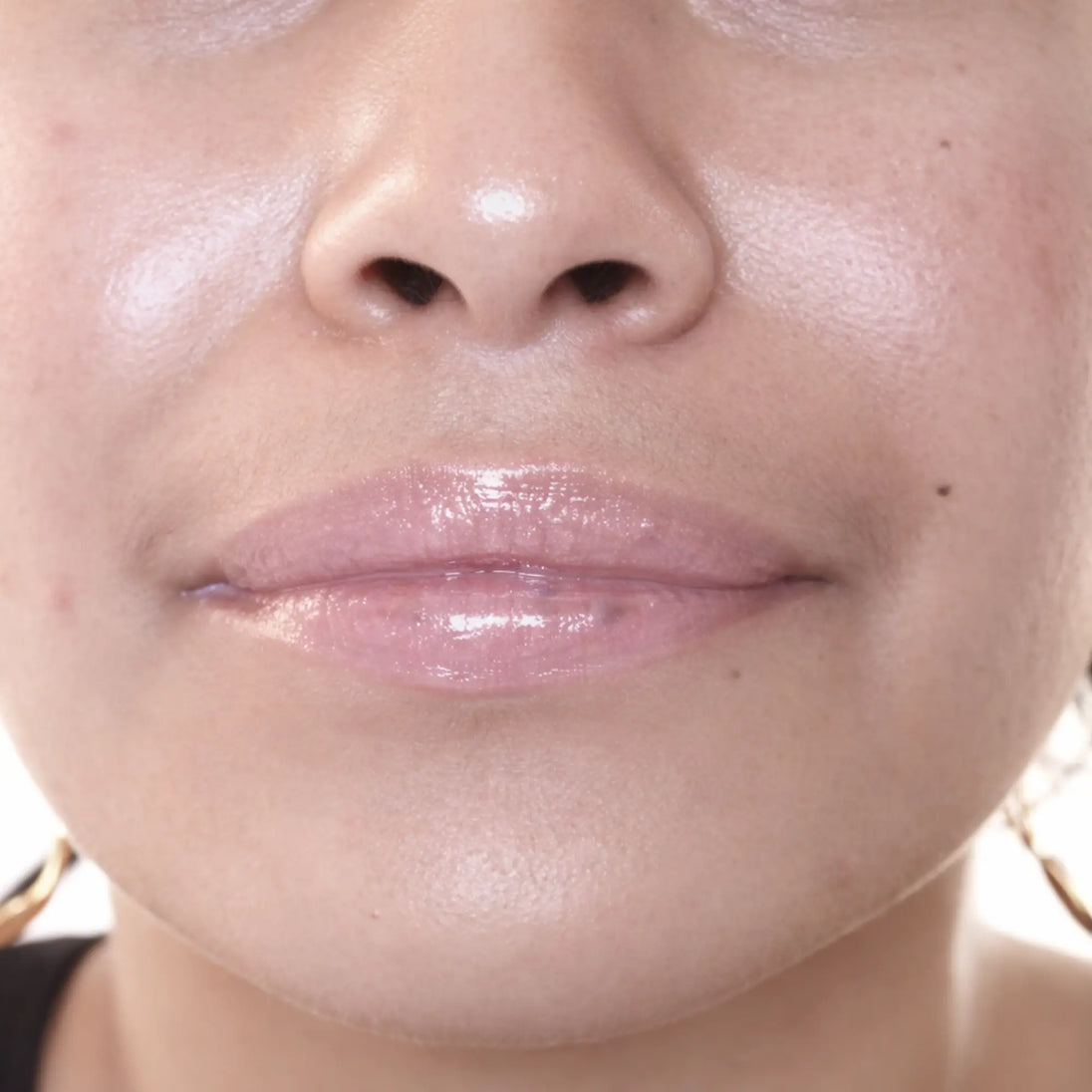 Woman with medium skin wearing Creamy Vanilla Lip Gloss, clear shimmering shade with nourishing botanicals