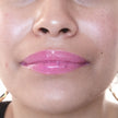 Woman with medium skin wearing Dragon fruit Gloss, clear shimmering shade with nourishing botanicals