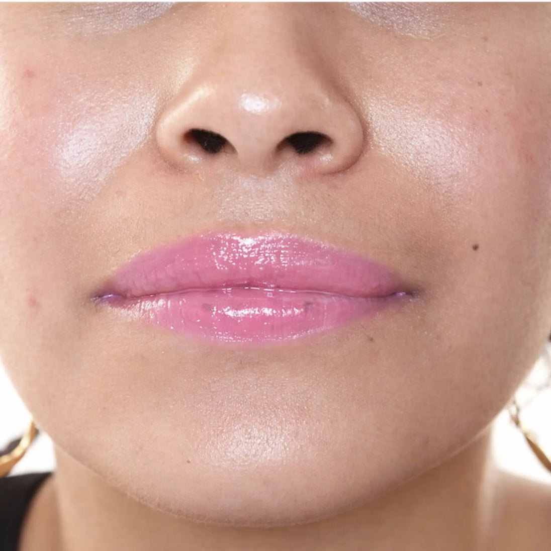 Woman with medium skin wearing luscious guava Lip Gloss, clear shimmering shade with nourishing botanicals