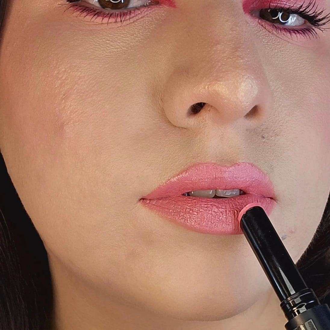 Woman with fair skin wearing Peony Lipstick, bright pink shade with nourishing botanicals