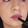 Woman with fair skin wearing Wisteria Lipstick, vibrant purple shade with nourishing botanicals