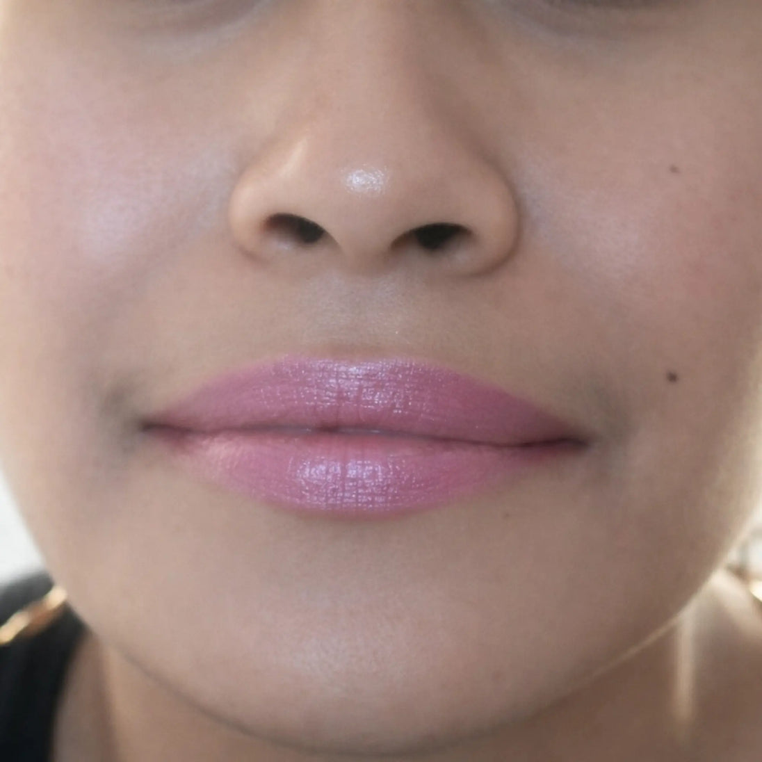 woman with medium skin wearing Wisteria Lipstick, vibrant purple shade with nourishing botanicals