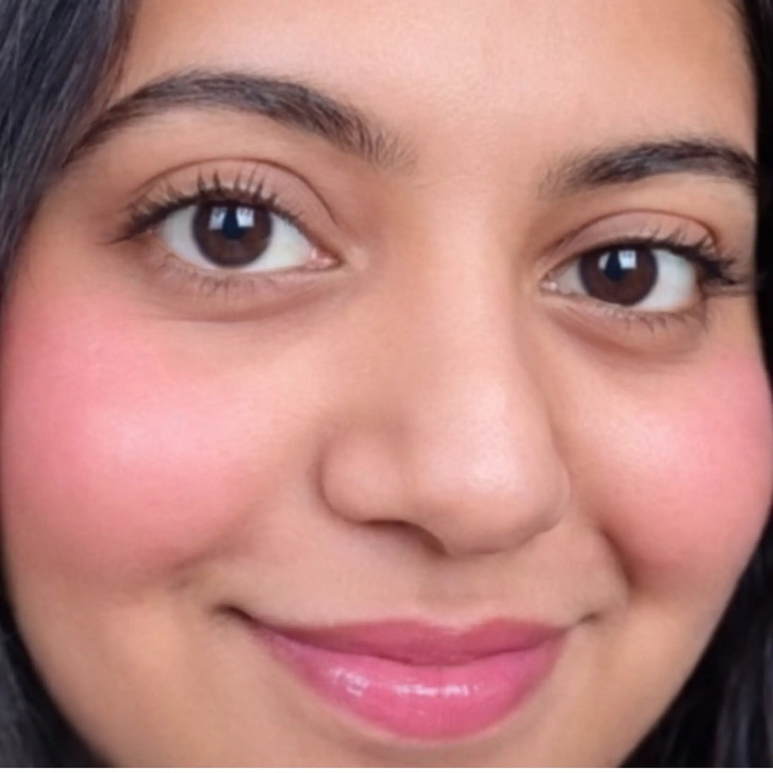 Close-up of a woman's face with dahlia color blush on cheeks