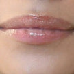 Woman with medium skin wearing caramel Lip Gloss, clear shimmering shade with nourishing botanicals