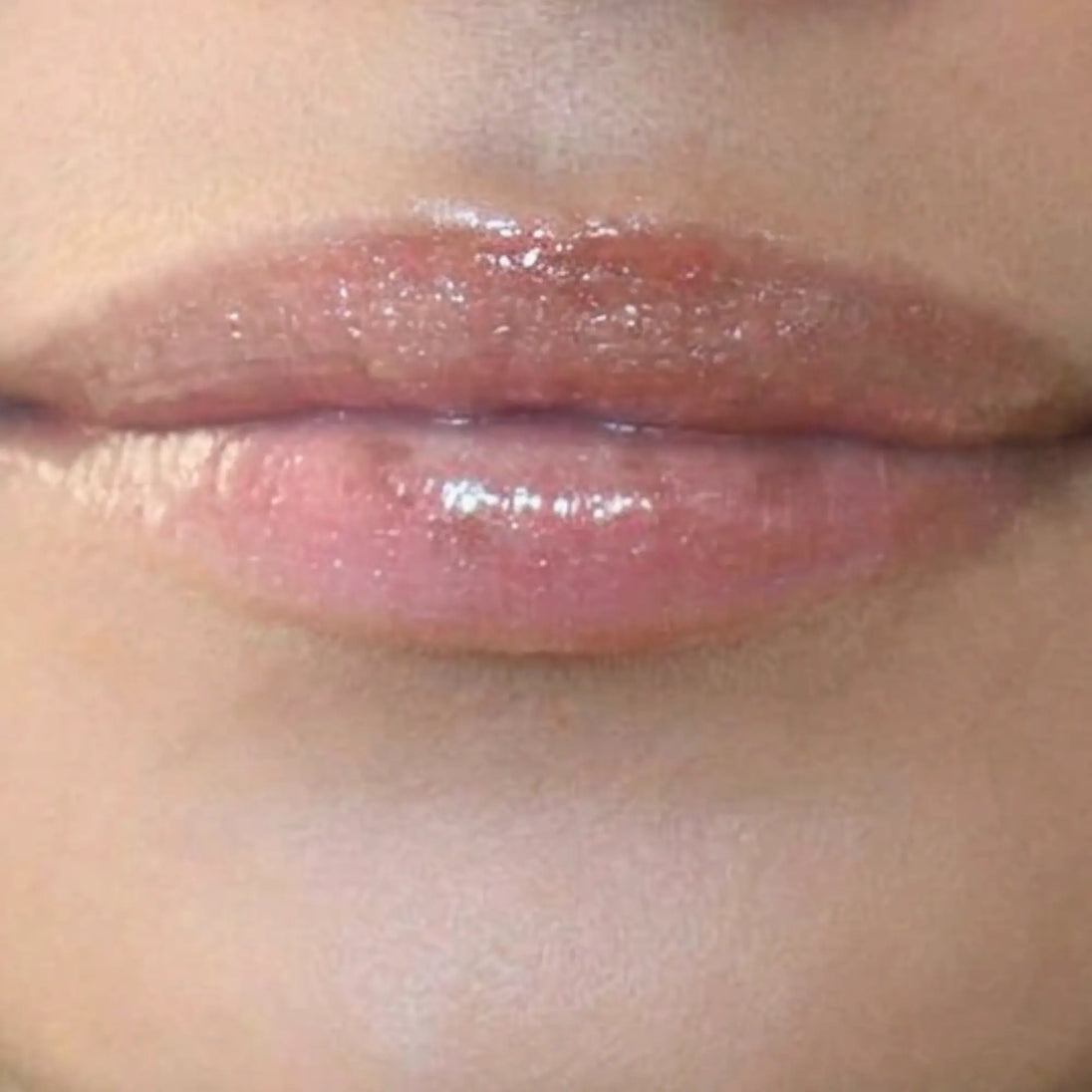 Woman with medium skin wearing caramel Lip Gloss, clear shimmering shade with nourishing botanicals