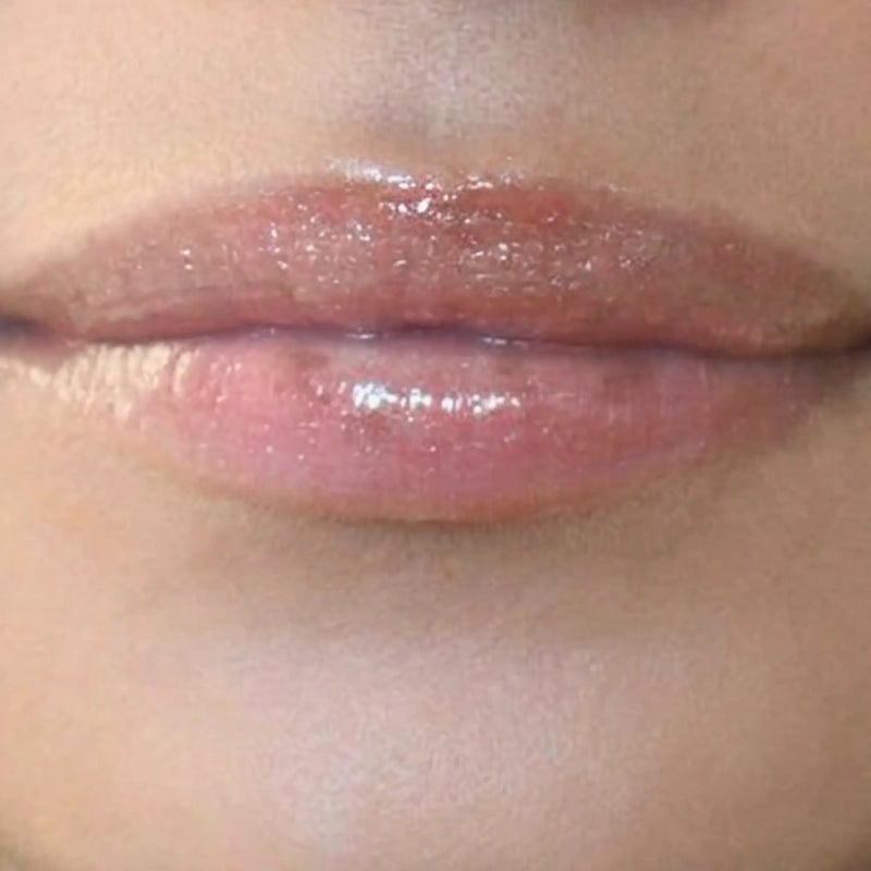 Woman with medium skin wearing caramel Lip Gloss, clear shimmering shade with nourishing botanicals
