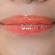 Woman with medium skin wearing cinnamon Lip Gloss, clear shimmering shade with nourishing botanicals