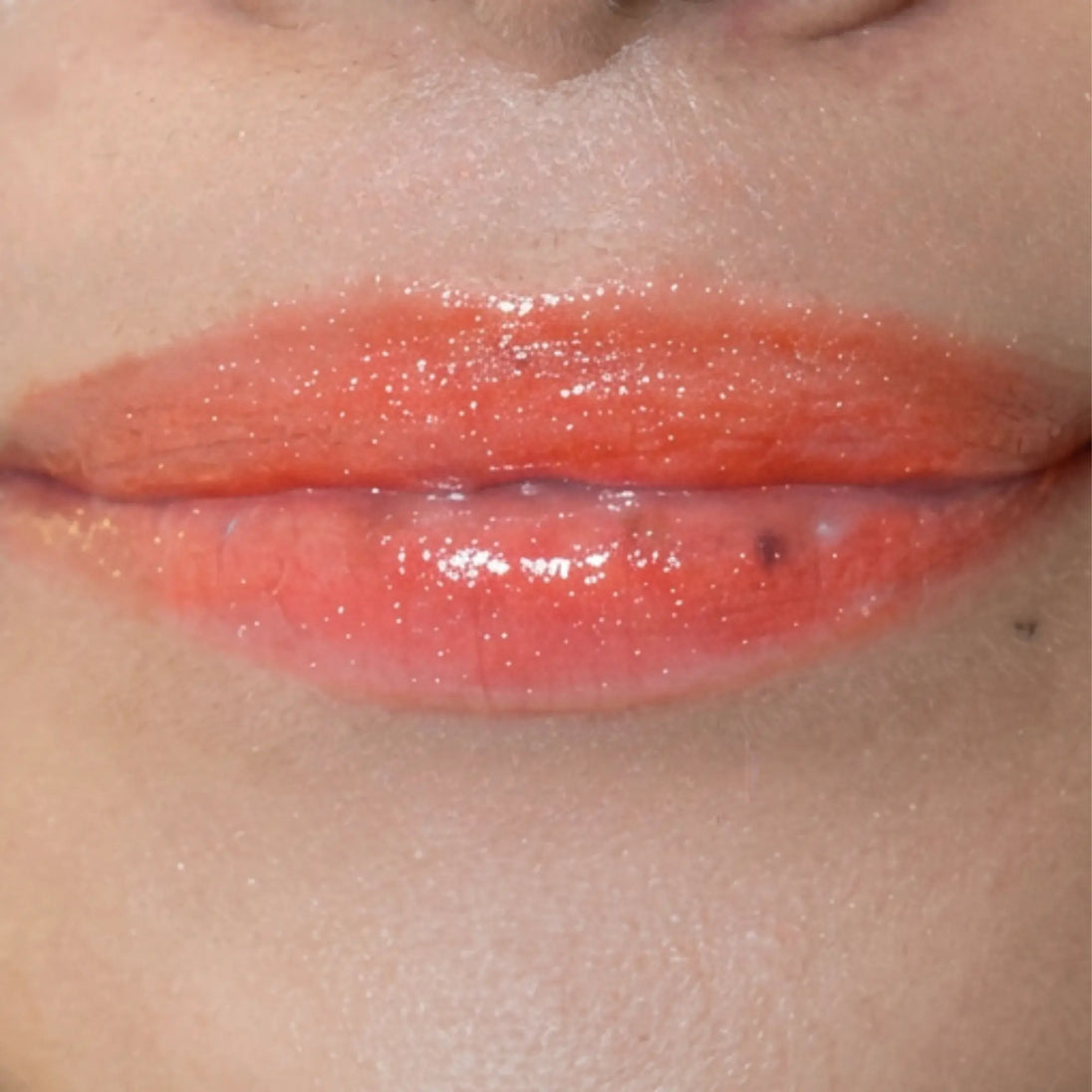 Woman with medium skin wearing cinnamon Lip Gloss, clear shimmering shade with nourishing botanicals