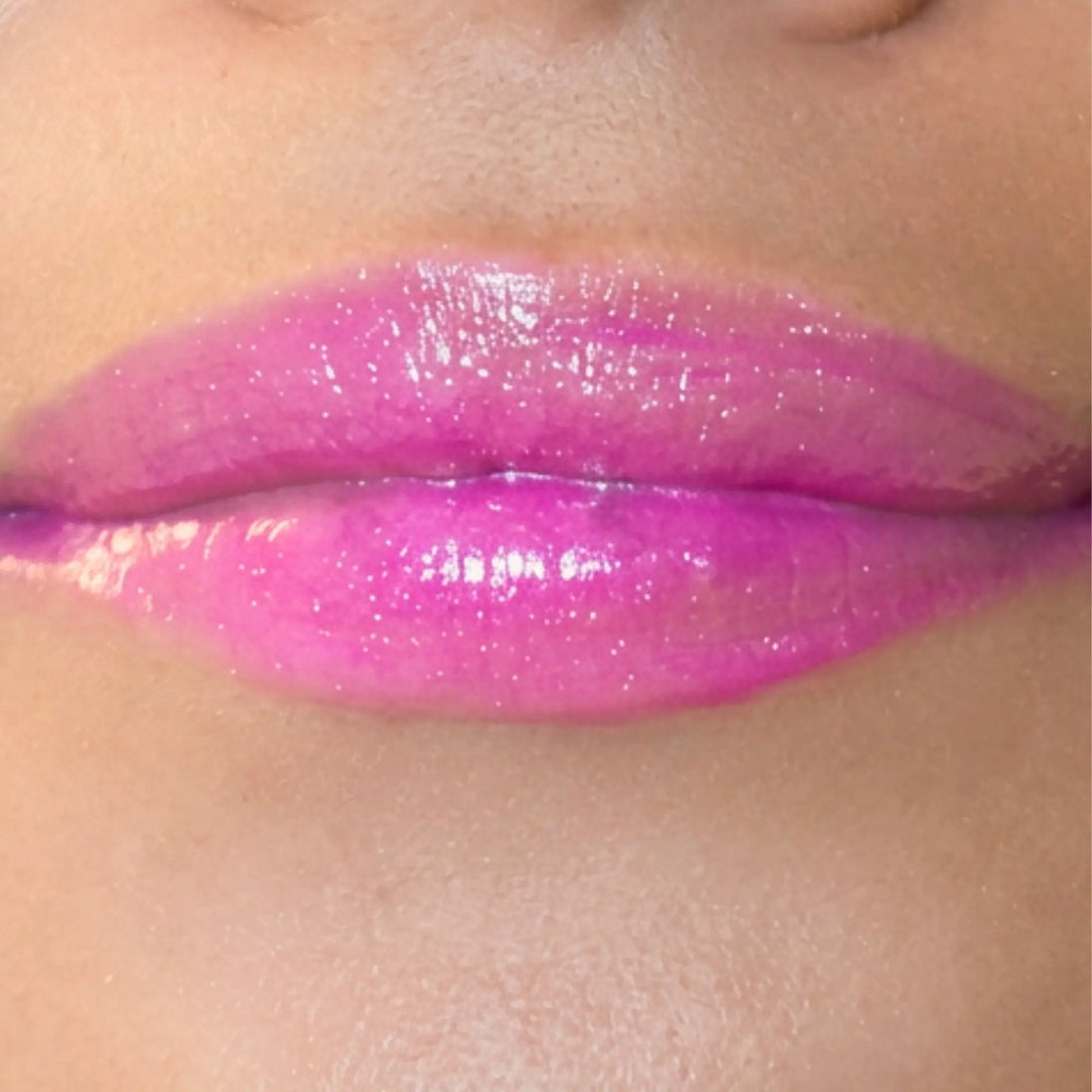 Woman with medium skin wearing Dragon fruit Gloss, clear shimmering shade with nourishing botanicals