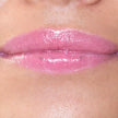 Woman with medium skin wearing luscious guava Lip Gloss, clear shimmering shade with nourishing botanicals