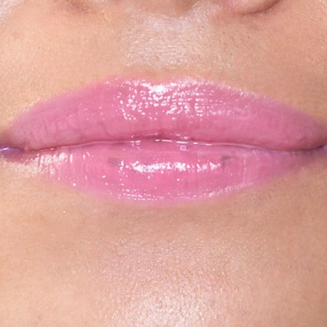 Woman with medium skin wearing luscious guava Lip Gloss, clear shimmering shade with nourishing botanicals