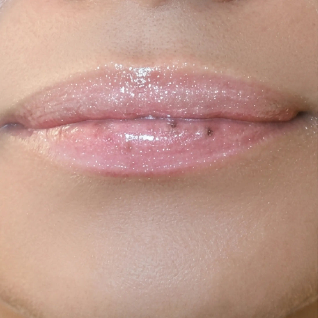 Woman with medium skin wearing Creamy Vanilla Lip Gloss, clear shimmering shade with nourishing botanicals